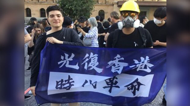 University of Queensland student Drew Pavlou (L) holds a banner supporting Hong Kong's pro-democracy movement