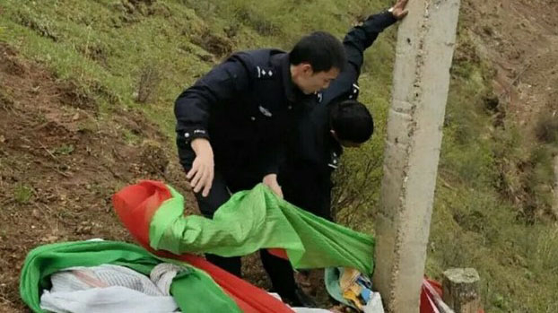 Chinese policemen take down a pole with prayer flags in an unidentified region of Tibet. 