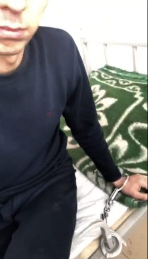 A screenshot from a video taken by Merdan Ghappar that purportedly shows his hand shackled to a bed while in detention in Xinjiang's Aksu province, in January 2020.